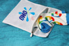 A white laundry bag with a logo, featuring colourful patterned socks peeking out from the zippered opening.
