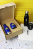 A drink bottle set featuring a blue metallic bottle, a black bottle, and a glass tumbler, all in packaging with logos.