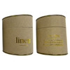 A large candle in a cylindrical kraft paper container with gold accents, labelled 'linen'.