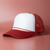 A red and white trucker cap with a structured front and mesh back. It features a curved brim and a logo.