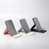 Three pocket mirrors in pink, grey, and black, each with a sleek, modern design and a stand.