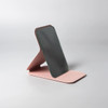 A compact pocket mirror with a stylish pink base and a dark reflective surface, featuring a design that allows for stand-up use.