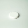 A round, white item tracker lies on a light surface, featuring a minimalistic design.