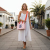 A woman in a white dress carries a pink EVA Holes Casual Tote Bag with an orange strap in an outdoor setting.