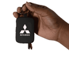 A hand holds a black keychain power bank featuring a logo, with keys attached.