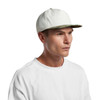 A two-tone camo cap with a white body and a camo-patterned brim, worn by a model in a plain white shirt.