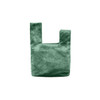 A green velvet wrist bag with a unique knot design and a simple, minimalistic shape. It features a logo.