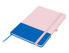 A pink and blue A5 notebook with a ribbon bookmark and an elastic closure. It features a branding logo.