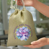 A medium jute gift bag in a natural tone, featuring a floral design and a logo.