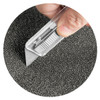 A hand holding a utility knife against a textured grey surface. The knife features a retractable blade.