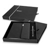 A black A5 notebook and silver pen set packaged in an elegant black box with a logo.