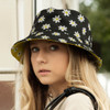 A reversible bucket hat featuring a black floral design with daisies and a contrasting yellow interior.