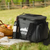 A dark grey cooler bag with a logo, surrounded by apples, a bottle of wine, and a picnic blanket.