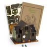A wooden model of a haunted house in dark colours, featuring a ghost and pumpkins, with assembly instructions.