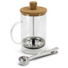 A clear glass coffee plunger with a cork lid, a stainless steel base, and a measuring spoon.