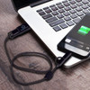 A braided charging cable in black, connected to a smartphone and a laptop on a wooden surface.