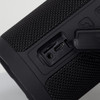 A black Bluetooth speaker featuring a textured surface, with ports for AUX and charging. It includes a logo.