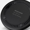 A wireless charger in black with circular design and ventilation holes, featuring a branding logo on the underside.