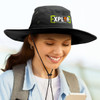 A wide-brim black hat with a logo, featuring a chin strap, worn by a person smiling while holding a phone.