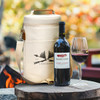 A cream-coloured cooler bag with a logo, accompanied by a bottle of red wine and a glass of wine.