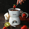 A white mini fondue set with melted chocolate, strawberries, marshmallows, and kiwi. Includes branding on the bowl.