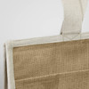 A jute cooler bag in natural brown, featuring a sturdy handle and a simple design, with a small logo on one side.