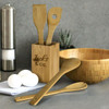Bamboo kitchen utensils in a holder, featuring a spatula, spoon, and fork. Includes a wooden bowl and white eggs.