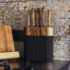 A wooden knife block with a black base, featuring five knives with wooden handles, placed against ornate wallpaper.