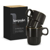 A set of two black stackable coffee cups displayed in a box, featuring a logo on the front.