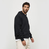 A black hoodie with a front pocket and a hood, displayed on a model standing sideways. Includes a logo.