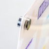 A magnetic fastener holding a clear, colourful planner, with various pastel shades visible on the surface.