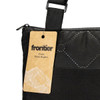 A black picnic blanket with a carrying strap and a tag featuring a brand logo.