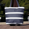A navy insulated cooler bag with white stripes, featuring sturdy handles and a branding logo.