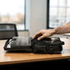 A black laptop bag with various compartments, open to reveal an organiser and space for accessories.