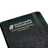 A black bound journal with a textured cover, featuring a logo and branding on the front.