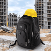 A black and grey 42L computer backpack with multiple compartments, placed on a construction site beside a yellow hard hat.