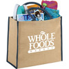 A large jute tote bag filled with magazines, a drink bottle, sunglasses, and colourful beach items, featuring a logo.