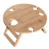 A round bamboo picnic table with cutouts for drink bottles and collapsible legs. It has a natural finish.