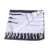 A Turkish beach towel with a dark grey and white striped design, featuring fringed edges and a small logo.