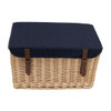 A wicker picnic basket with a navy blue fabric lid and brown leather straps, featuring a logo on the front.