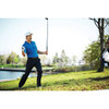 A man in a blue Kiso short sleeve polo shirt swings a golf club on a grassy area by a water body.