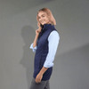 A woman wearing a navy lightweight packable insulated puffer vest, paired with a light blue shirt and grey pants.