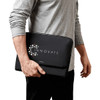 A black laptop caddy being held by a person, featuring a logo on the front.