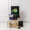 A gourmet gift pack featuring a wooden serving board, assorted gourmet snacks, olive oil, and a jar of jam, all in a black box.