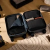 A dark blue packing cube opened, featuring multiple compartments and black mesh dividers, resting on a light textured surface.