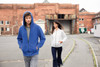 A blue men's zip hoodie and a white women's zip hoodie are worn by models in an urban setting.