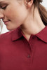 A maroon polo shirt featuring a collared neckline and button details, worn by a model displaying a profile view.