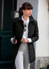 A stylish black women's jacket is featured, worn over a white shirt and grey pants, accessorised with sunglasses.