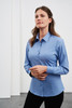 A woman wearing a light blue button-up shirt with long sleeves, featuring a logo on the chest.