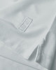 A white polo shirt featuring a hem split and a logo. The fabric has a textured appearance.